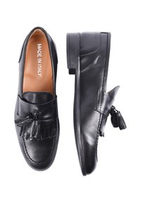 Mocassini in pelle nera con nappine, texture liscia, tacco leggero e etichetta 'Made in Italy' sulla soletta. Design classico e versatile.