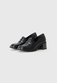 Svarta läderloafer med en låg klack, med en sydd design och ett brett band över fronten för ytterligare detaljer.