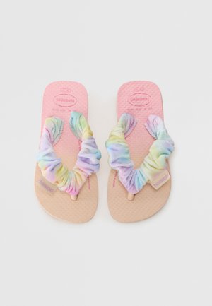Havaianas sussud, roosa kummist tallaga, millel on mitmevärvilised riidest rihmad kokku kogutud disainiga ja pastelltoone.