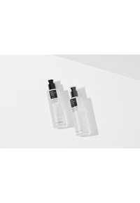 Deux bouteilles en plastique transparent avec des pompes noires, présentant des étiquettes minimalistes en noir et blanc. L'une des bouteilles a un capuchon transparent.