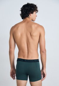 Boxer da uomo di colore verde scuro con elastico nero sul quale è inciso in maiuscolo "BJÖRN BORG". Tessuto morbido e design aderente.