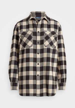 Chemise en flanelle à carreaux noire et beige avec des manches longues, un devant boutonné et deux poches sur la poitrine. Texture douce et motif à carreaux classique.