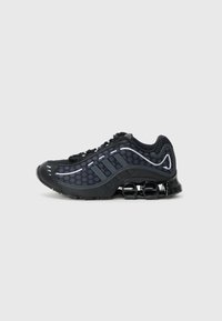 Black athletic shoes with mesh upper featuring circular patterns. Accented with gray stripes, a cushioned sole, and springy black heel supports.