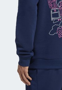 Marineblauer Sweatshirt mit gerippten Bündchen und Saum, auf dem Rücken mit einem grafischen Design in Rosa und Weiß. Weicher, strukturierten Stoff und lässiger Schnitt.