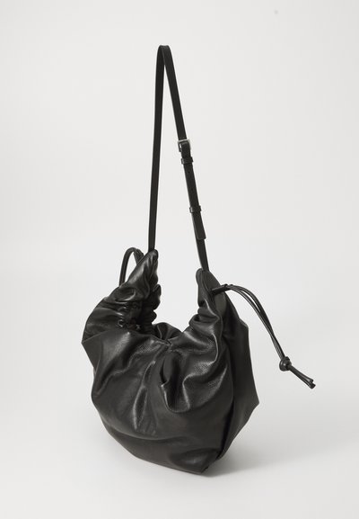 Black leather handbag with a gathered design, adjustable strap, and drawstring closure, featuring a soft texture and elongated shape.