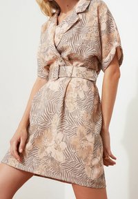 Blumendruck-Kurzkleid in Beige und zartem Rosa mit einem kragenlosen Ausschnitt, kurzen Ärmeln und einem passenden Gürtel in der Taille. Strukturierter Stoff.