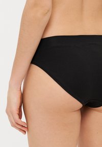 Chiloți hipster din bumbac negru, cu o bandă elastică netedă la talie, având cusături minimale și un design fără cusături în spate.