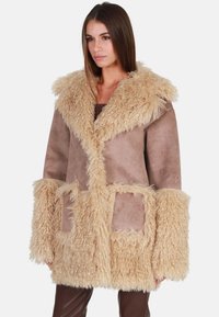 Nepbonten jas in tan en beige, met een fluffy kraag, oversized mouwen en zakken met een patch, die een suède textuur combineert met zachte accenten.