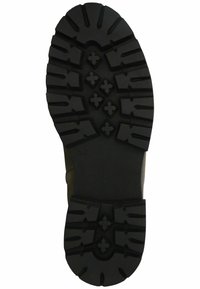 Suela de bota de goma negra con patrones de relieve profundos, que incluyen formas de cruz elevadas y surcos para tracción, con un fondo texturizado.