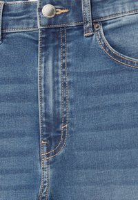 Jeans in denim blu con zip, chiusura a bottone metallico e cuciture arancioni a contrasto. Include tasche frontali con cuciture curve.