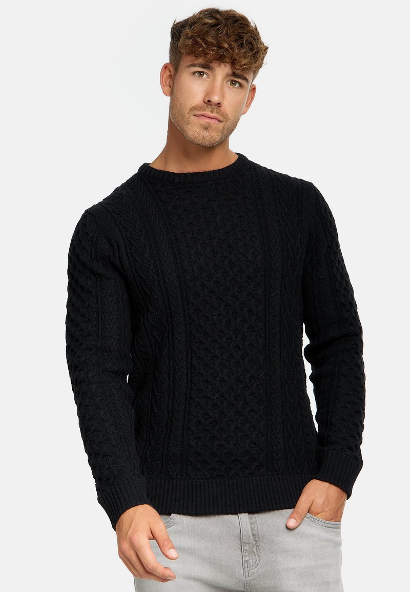 Schwarzer Strickpullover mit strukturierten Zopfmustern, rundem Ausschnitt sowie gerippten Bündchen und Saum. Geeignet für legere Anlässe.