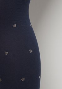 Granatowy materiał z teksturowanym wzorem, z małymi, błyszczącymi srebrnymi sercami równomiernie rozmieszczonymi na powierzchni.