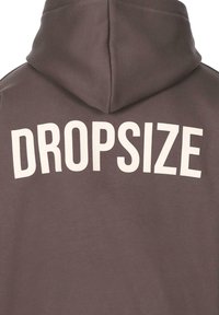 Grå hættetrøje med hvid "DROPSIZE" tekst på ryggen, med standard hætte design og en blød, glat tekstur.