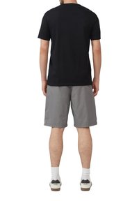 Czarny t-shirt z krótkim rękawem w połączeniu z jasnoszarymi szortami, noszony z białymi skarpetkami i casualowymi sneakersami. Prosty wzór, miękki materiał, luźny krój.