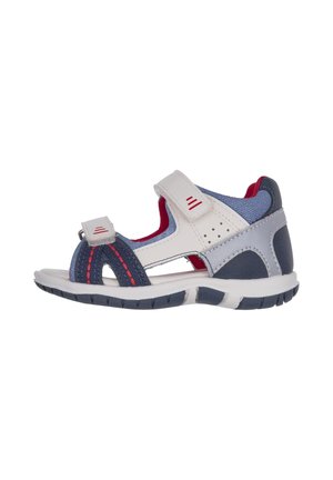 Sandale légère avec une tige blanche et marine, des accents rouges, des sangles réglables, un bout ouvert et une semelle en caoutchouc texturée.