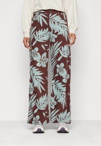 Pantalon large marron à motifs avec des motifs floraux et feuilles bleu clair, doté d'une fermeture à boutons et de poches avant.