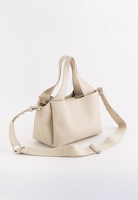 Beige læder håndtaske med en struktureret form, dobbelte håndtag og justerbar rem. Har en tekstureret overflade og en lynlåslukning i toppen.