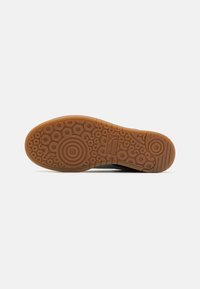 Rubber sole with a circular pattern and textured grip. Orange-brown color with a smooth finish and branding on the side.