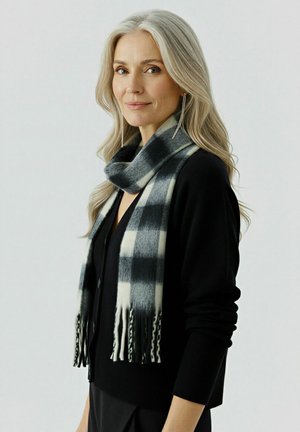 Black and white checkered scarf with fringed ends, made of soft material, draped around the neck of a model wearing a black cardigan.