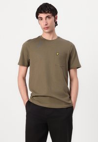 Tricou verde măsliniu cu guler rotund, realizat din bumbac, având un buzunar pe piept și un mic accent cu logo galben pe partea stângă.