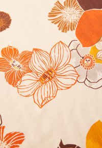Tejido floral que presenta grandes flores en tonos naranja y marrón con detalles de líneas finas sobre un fondo crema. Textura suave y colores vibrantes.