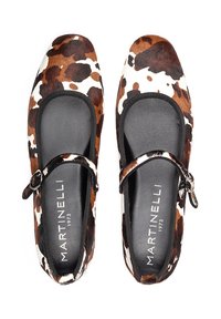 Ballerines avec un motif en cuir de vache brun et blanc, bout rond, doublure intérieure noire et une sangle avec un détail à boucle.