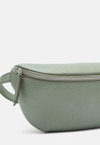 Zielona skórzana saszetka z metalowym zamkiem błyskawicznym i boczną rączką. Gładka tekstura z wytłoczonym logo po boku.