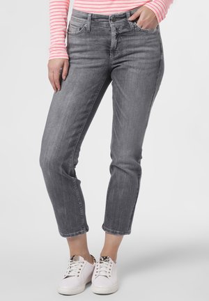 Personne portant un jean gris court, des baskets blanches avec des accents imprimé animal et un haut manches longues rayé rose et blanc.