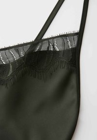 Close-up of dark green camisole with thin straps and a sheer lace trim along the top edge.