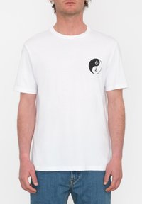 Witte katoenen t-shirt met korte mouwen, voorzien van een cirkelvormige zwart-witte graphic op de borst met een yin-yang ontwerp.
