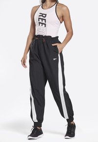 Black lightweight joggers with white side stripes, elastic waistband, and pockets, paired with a pink tank top featuring black logo text.