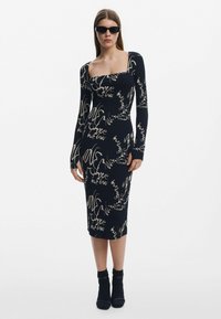 Pikkade varrukatega must ribikleit, millel on ruudukujuline kaelus ja valge trükitud kursiivkirja tekst. Tihedalt liibuv, midi-pikkusega disain.