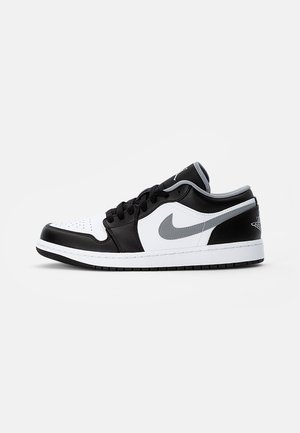 Niskie czarno-biało-szare buty Nike Air Jordan z czarnymi sznurówkami i szarym logo Nike na białym tle.