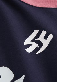 Marineblåt stof med en blød tekstur, der har et stort hvidt grafisk logo og en kontrasterende lyserød ribkant ved halsen.