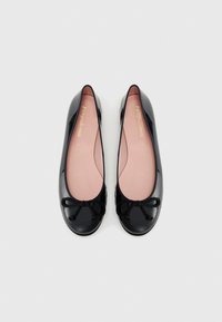 Ballerines en cuir verni noir avec un bout arrondi, des semelles intérieures roses et un nœud noir décoratif à l'avant. Fini lisse et brillant.