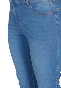 Jeans de mezclilla azul con una textura suave, que presentan un diseño clásico, bolsillos estándar y detalles de costura sutil a lo largo de las costuras.