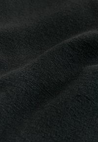 Gros plan d'un tissu noir montrant une surface douce et texturée avec des plis légers et de fines mailles.