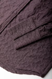 Camicia a maniche lunghe in tessuto strutturato di un profondo viola, con un motivo geometrico, chiusura a bottoni e dettagli ai polsi. Tessuto morbido e design strutturato.