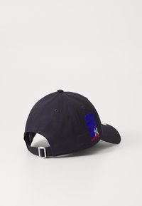Cască de baseball de culoare bleumarin, fabricată din twill de bumbac, având text brodat în violet și roșu, cu curea ajustabilă în spate.