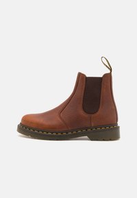 Brauner Leder Chelsea-Stiefel mit elastischen Seitenpaneelen, texturierter Oberfläche, runder Zehenform, kontrastierenden gelben Nähten und einer Zuglasche.