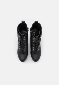 Botines negros hechos de cuero suave con cordones en la parte delantera, cremalleras en los laterales y ojales de bronce. Punta redonda y panel lateral texturizado.