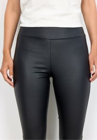 Svarta hög midjade leggings gjorda av ett slätt, stretcht material. Har en elegant design utan synliga sömmar.
