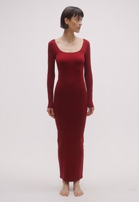 Dlhé šaty s dlhým rukávom v tmavočervenej farbe, vyrobené z hladkej, pružnej tkaniny. Majú priliehavý strih, výstrih dookola a lem po členky.