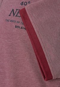 Bordowy materiał o teksturowanym splocie, z kontrastowym, ciemnoróżowym wykończeniem i czarnym nadrukiem. Wzmocnione szwy widoczne na krawędziach.