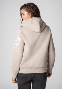 Beige hoodie met een textuurstof, voorzien van witte grafische tekst op de mouwen en een ribgebreide zoom en manchetten.