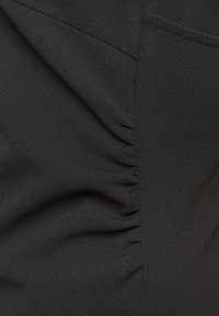 Crni materijal sa mekanom teksturom koji sadrži nabore sa strane i glatku završnu obradu. Dizajn naglašava oblik s elegantnim, minimalističkim izgledom.