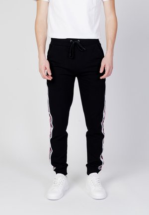 Czarne spodnie dresowe z białymi i czerwonymi paskami po bokach, wykonane z mieszanki bawełny, z elastycznym pasem ze sznurkiem i ściągaczami przy kostkach.