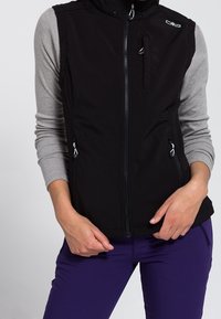 Czarna bezrękawnik w materiale softshell z szarymi długimi rękawami. Posiada wysoki kołnierz, kieszenie na zamek i sportowy krój.