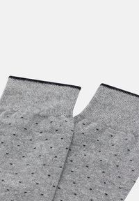 Šedé ponožky s tečkovaným vzorem a malými černými tečkami, vyrobené z texturované látky, s kontrastním tmavým pruhem nahoře.