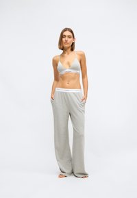 Grå bralette og vide bukser laget av mykt stoff. Braletten har tynne stropper og logo elastikk. Buksene har sidelommer og elastisk midje.